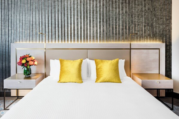A hotel room with a large bed, two nightstands, and a vase of flowers. - Paradox Sydney (Sydney)