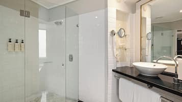 A modern bathroom with a glass-enclosed shower, a large mirror, and a white sink.