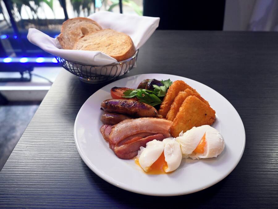 Un plato de comida para el desayuno que incluye huevos, tocino, salchichas y tostadas sobre una mesa.