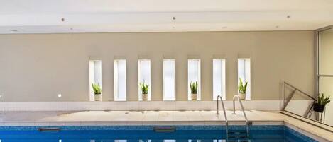 Une piscine offrant une vue dégagée sur le plafond, une échelle et des plantes en pot disposées sur le rebord de la fenêtre.