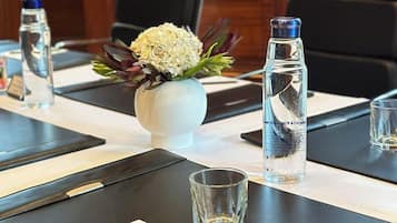 A conference room with a long table, water bottles, a vase with flowers, and black chairs.