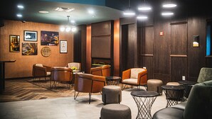 A modern lounge area with wooden panel walls, multiple seating options including sofas and chairs, and a fireplace. - Delta Hotels by Marriott Cincinnati Sharonville (Sharonville)