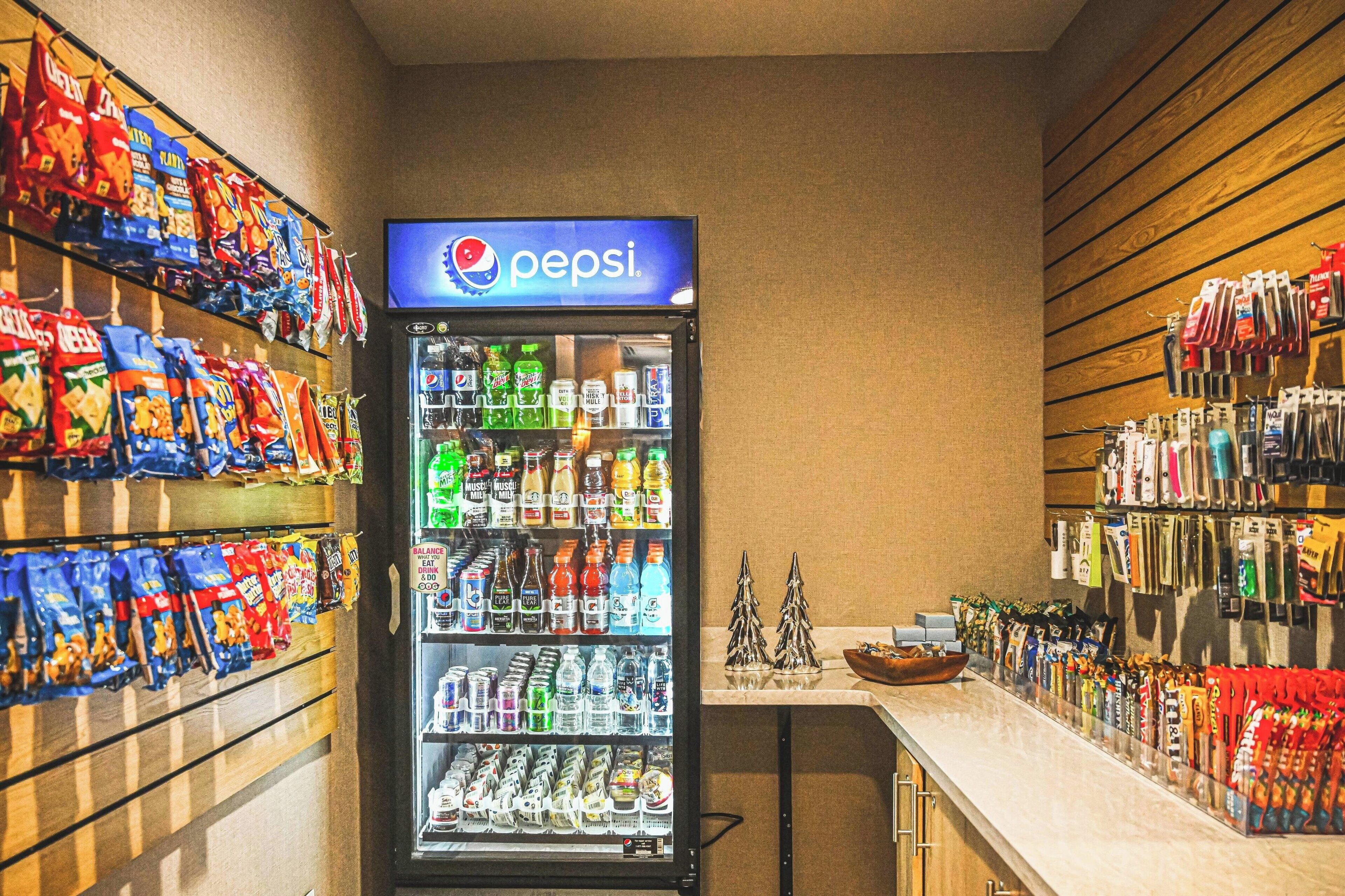 A vending machine stocked with snacks and beverages, including Pepsi, and shelves with various packaged goods.