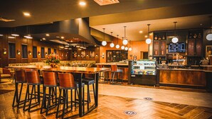 A restaurant with a bar area, wooden flooring, and modern lighting fixtures. - Delta Hotels by Marriott Cincinnati Sharonville (Sharonville)