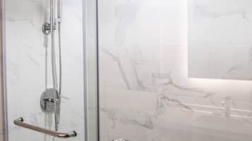 Een douchecabine met glazen wanden, een chromen handgreep en een handdouche.