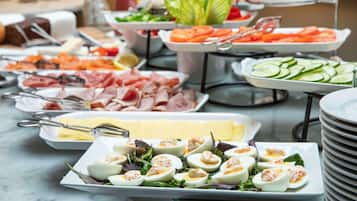 Un bufé con diversas opciones de comida, incluyendo carnes, quesos y ensaladas.