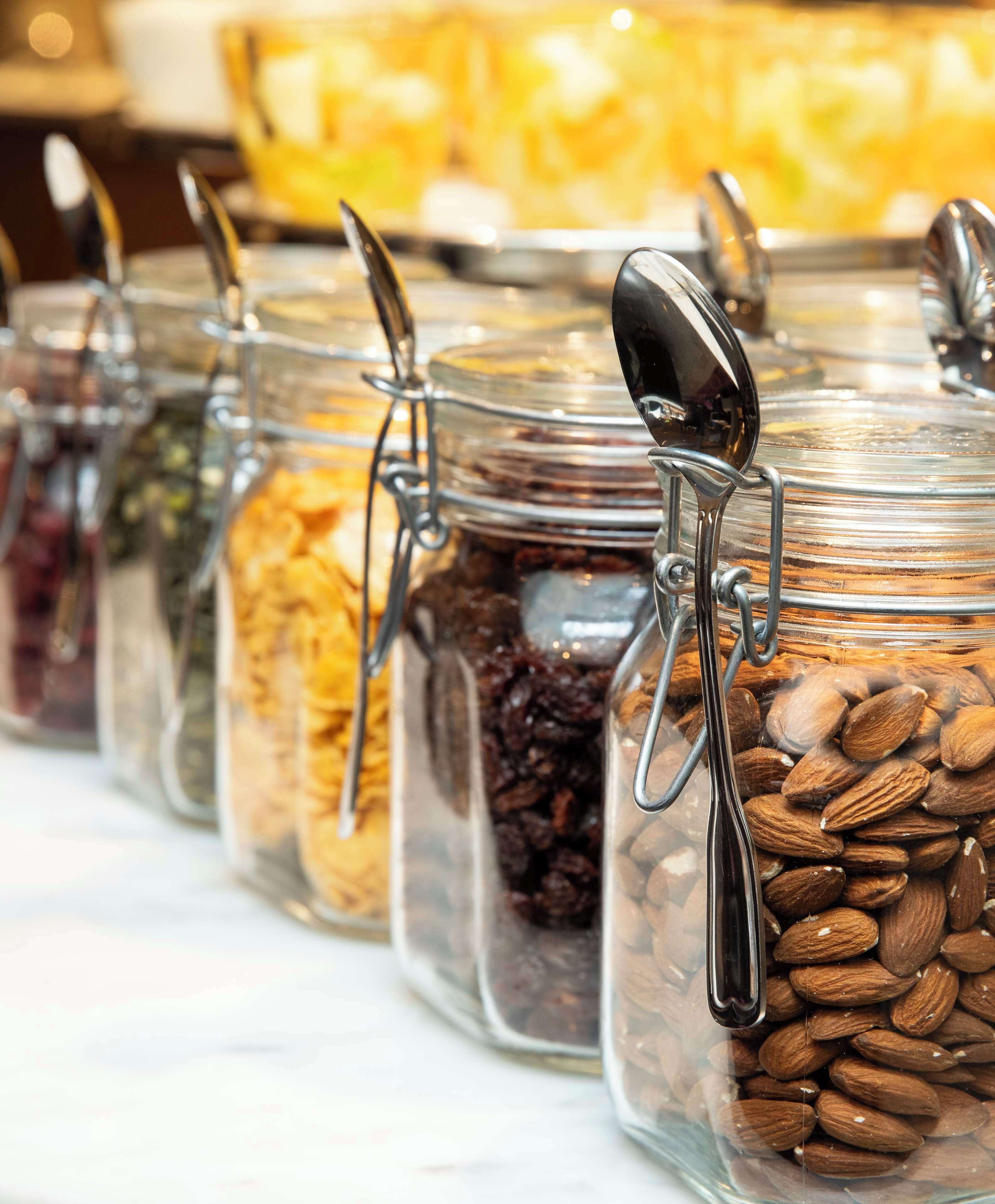 A row of glass jars with metal clasps, each containing different types of nuts and dried fruits.