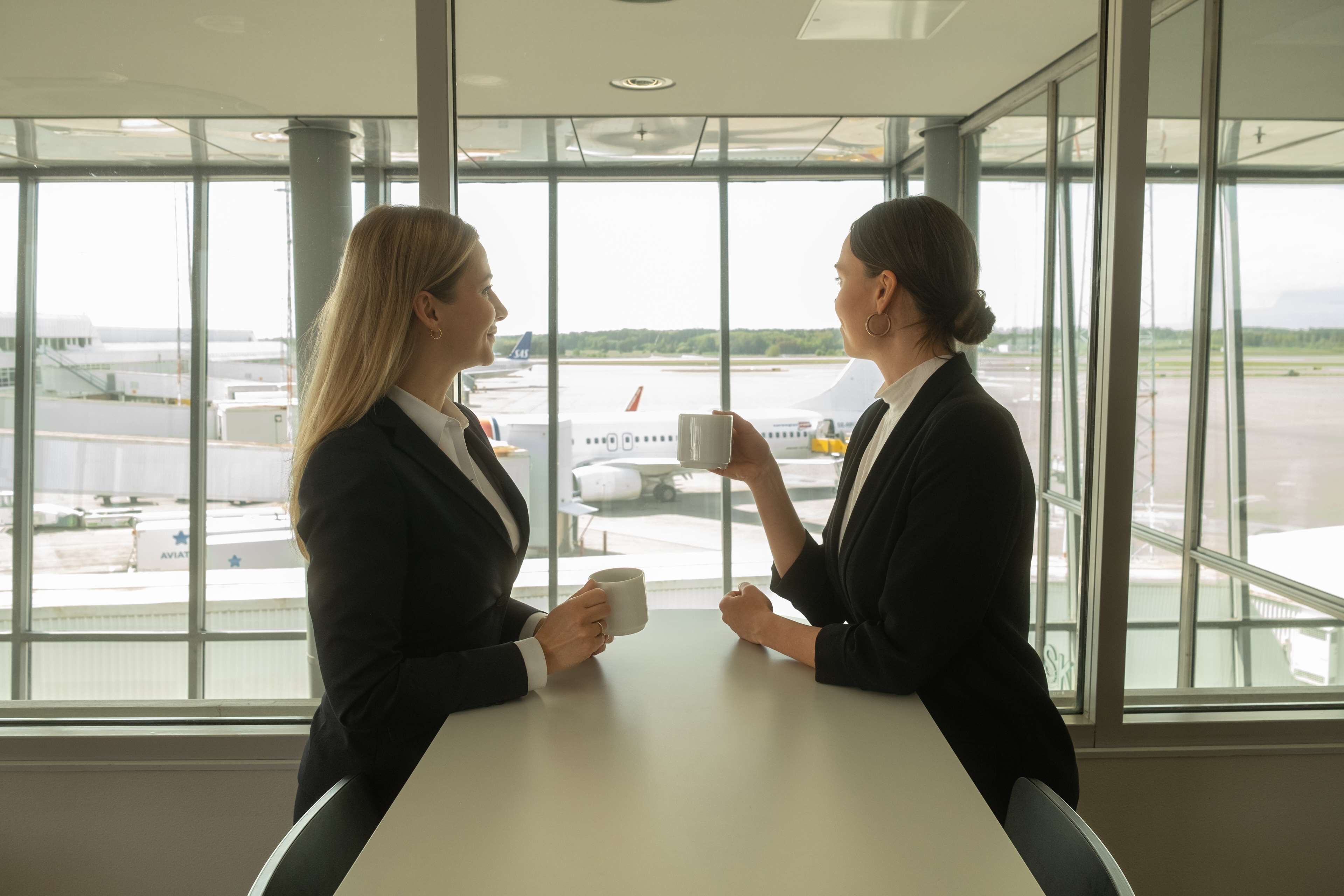 Due persone sedute a un tavolo con vista sull'aeroporto sullo sfondo.