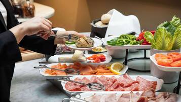 Ein Buffet mit verschiedenen Speisen, darunter Fleisch, Gemüse und Salat.