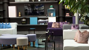 A modern lounge area with sofas, ottomans, and hanging lights. A sign reads "Radisson Blu Airport Stockholm-Arlanda."