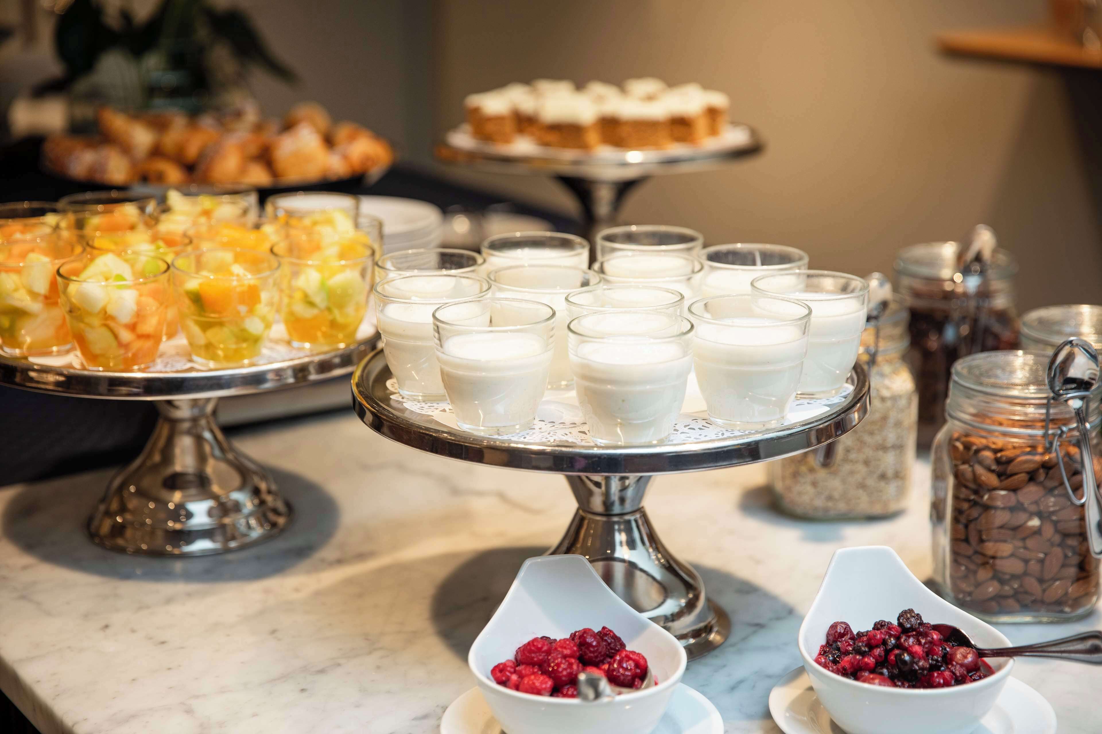 Un buffet con diverse pietanze, tra cui frutta, yogurt e pasticcini.