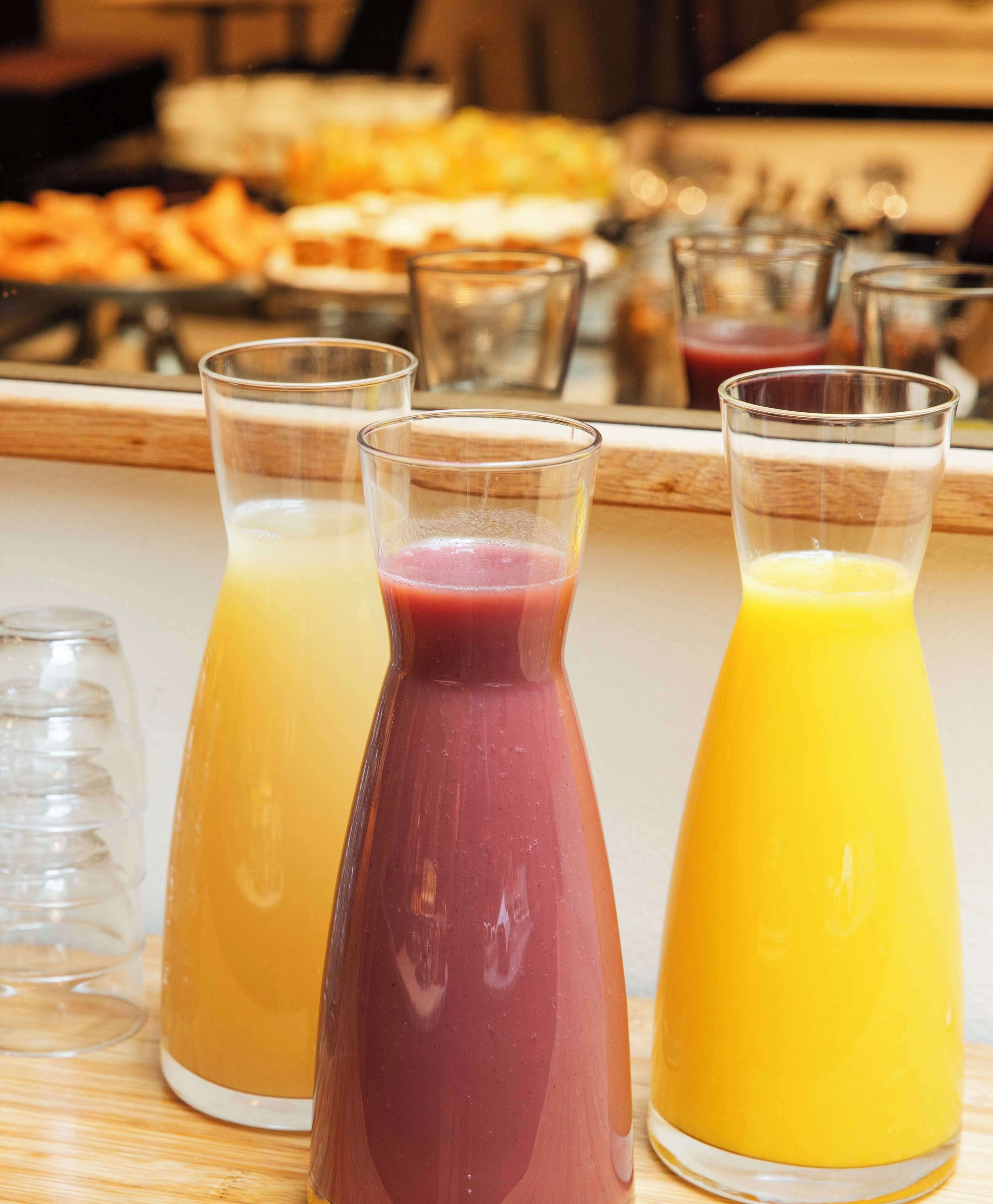 Three glass containers with different colored beverages on a wooden surface.