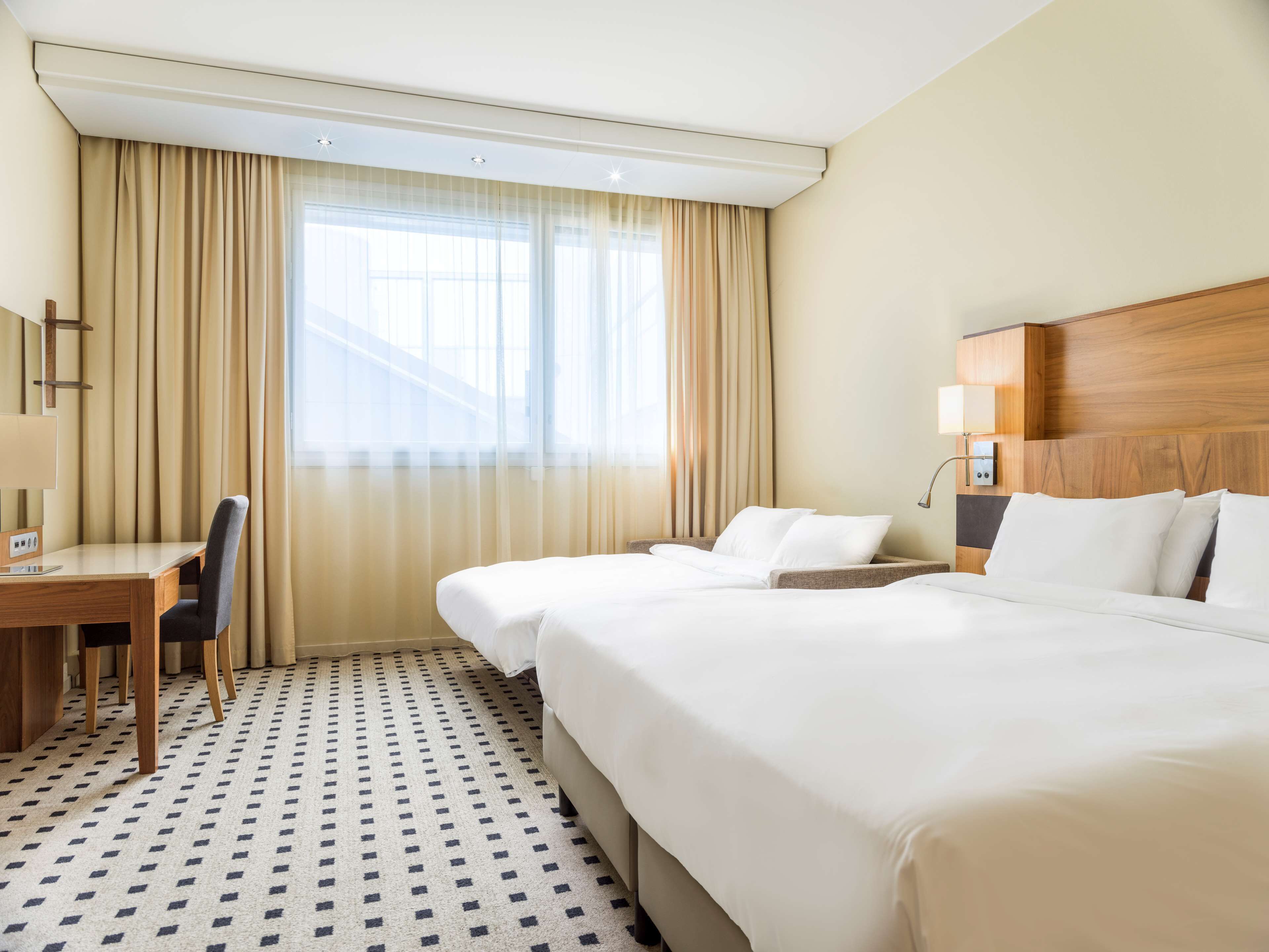 A hotel room with two beds, a desk, and a chair.