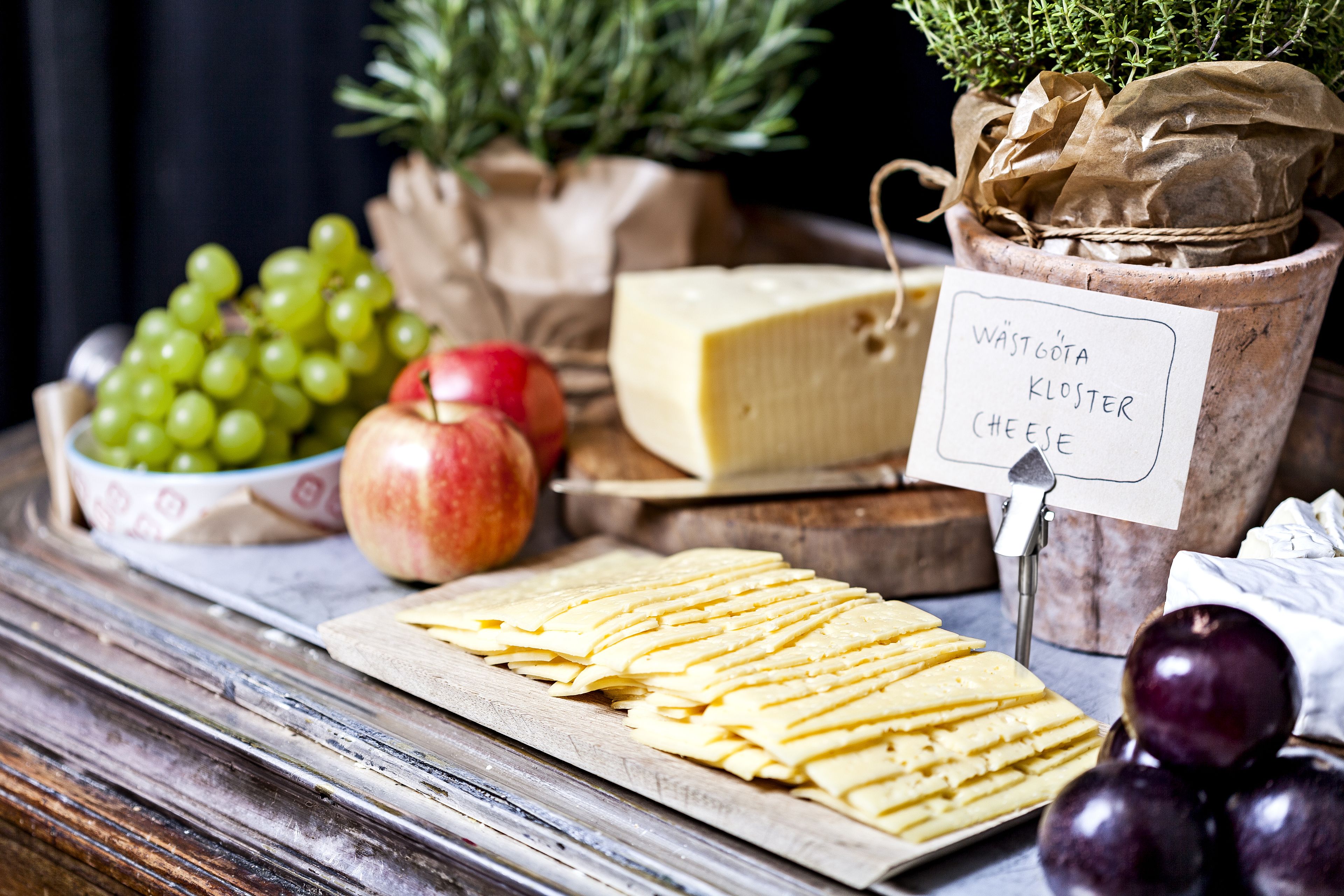 A cheese board with various cheeses, grapes, and an apple.
