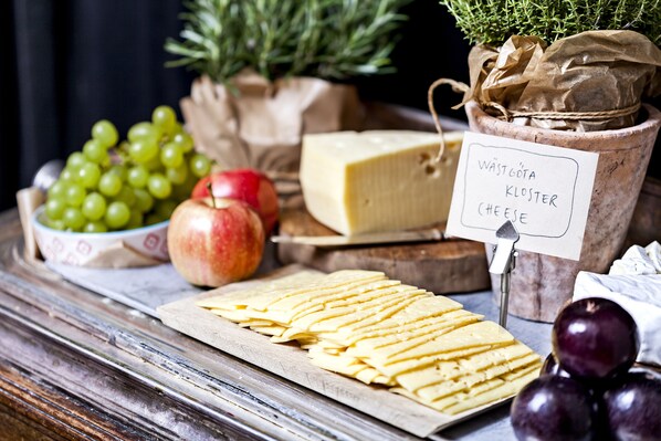 Una tabla de quesos con diferentes tipos de queso, uvas y una manzana.
