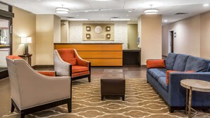 A lobby with a reception desk, seating area, and a patterned carpet.