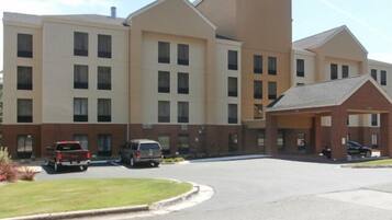 A multi-story hotel with a central courtyard, parking area, and a covered entrance.