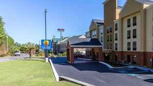 A hotel entrance with a Comfort Inn sign, a covered parking area, and a clear sky.