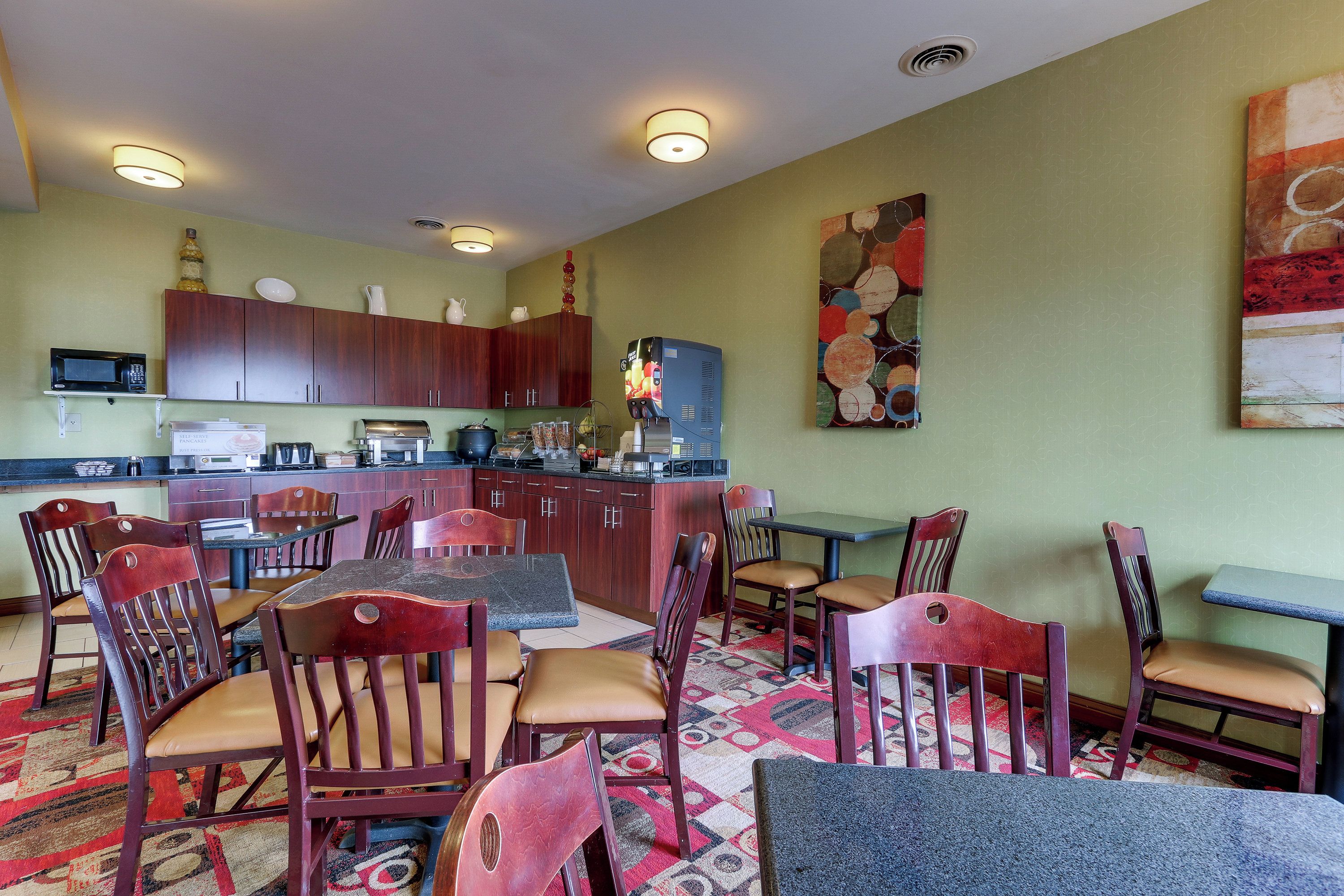 A dining area with wooden chairs and tables, a kitchen with wooden cabinets, and a microwave on the counter.