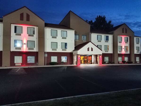 A multi-story hotel with a central entrance and parking lot.