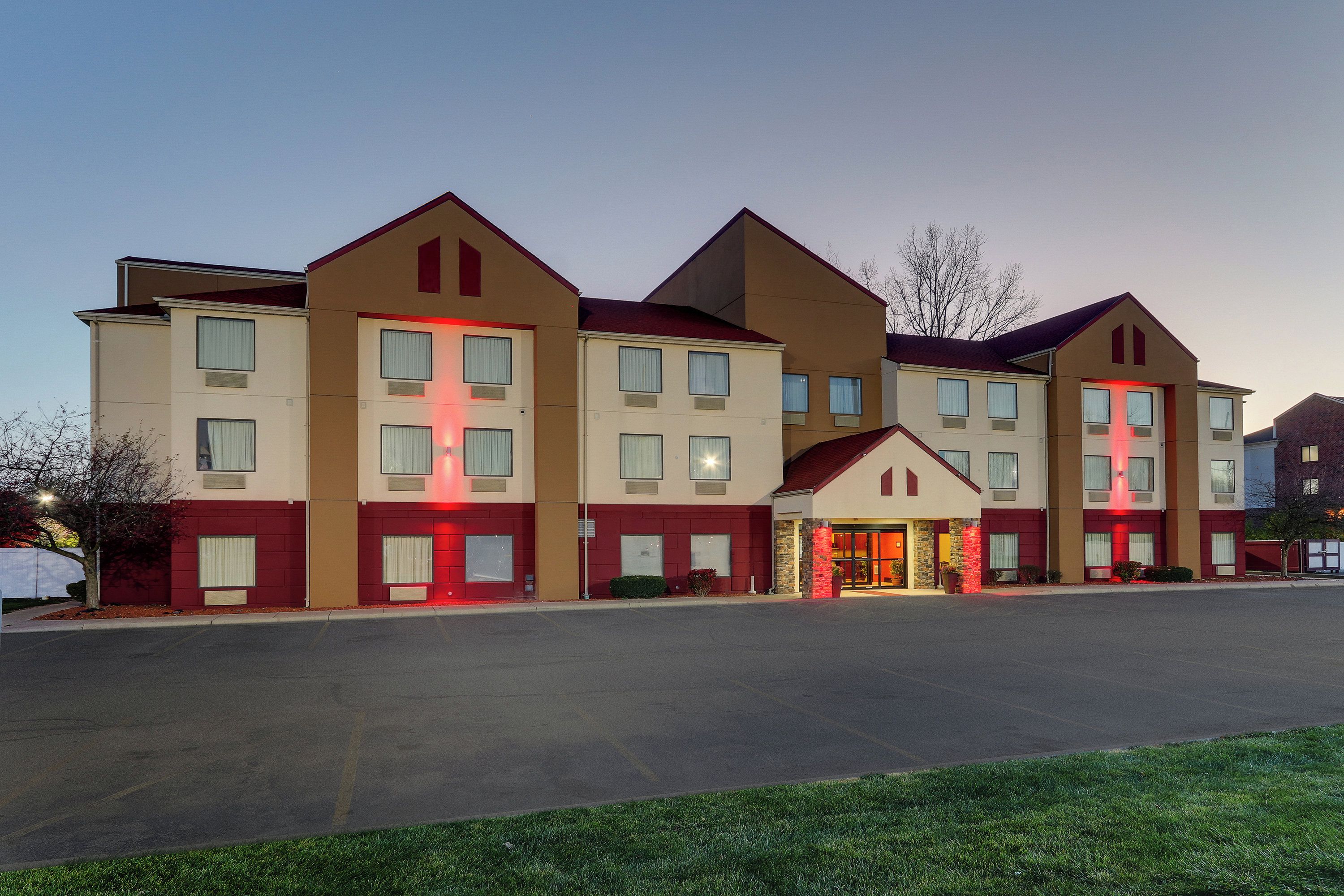 Hotel com vários andares, entrada central e unidades individuais de cada lado.