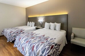 A hotel room with two beds, a nightstand, a lamp, and a chair. - Red Roof Inn Springfield, OH (Springfield)