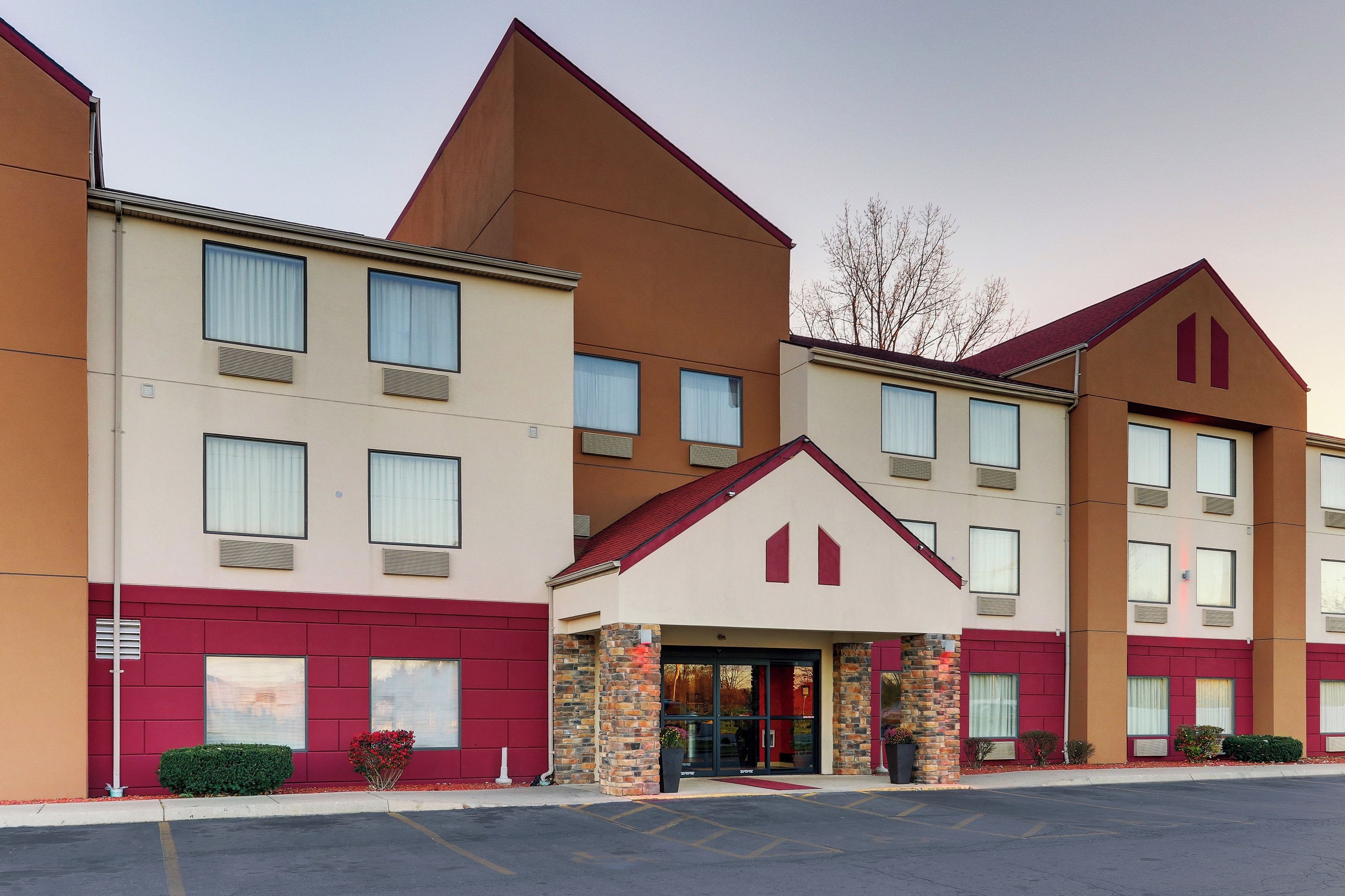 A multi-story hotel with a central entrance, large windows, and a parking lot.