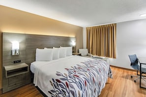 A hotel room with a bed, bedside tables, a desk, a chair, and a window with curtains. - Red Roof Inn Springfield, OH (Springfield)