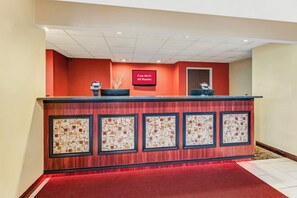 A reception desk with a digital display, a red carpet, and a wall with framed artwork.