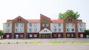A multi-story hotel with a symmetrical facade, a central entrance, and a parking lot in front. - Red Roof Inn Springfield, OH (Springfield)