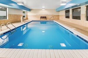 A swimming pool with clear blue water, surrounded by beige tiles and blue accents. - Red Roof Inn Springfield, OH (Springfield)