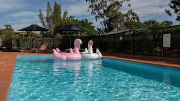 Una piscina al aire libre, sillones reclinables de piscina