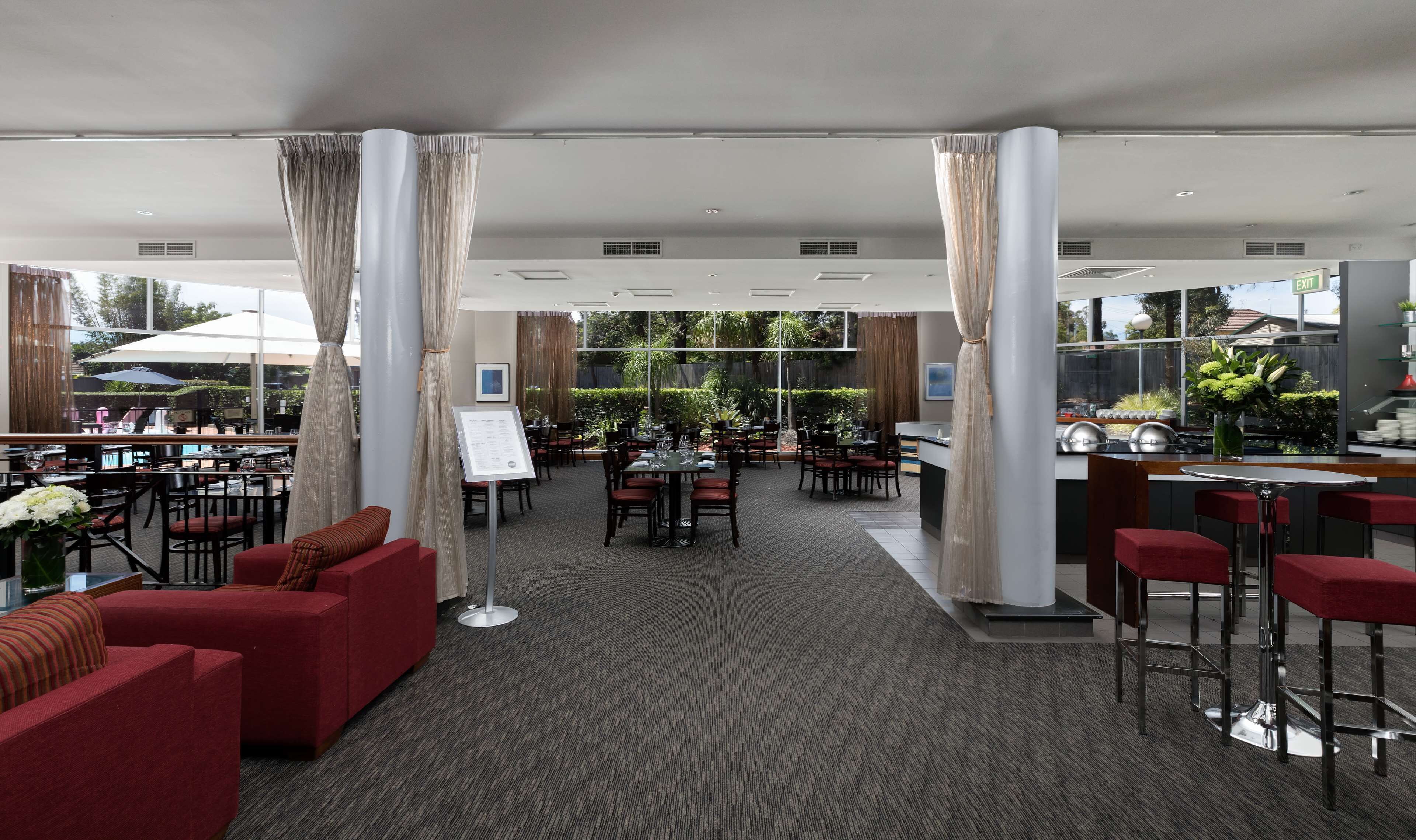 A hotel lobby with a bar area, seating, and a view of the outdoors.