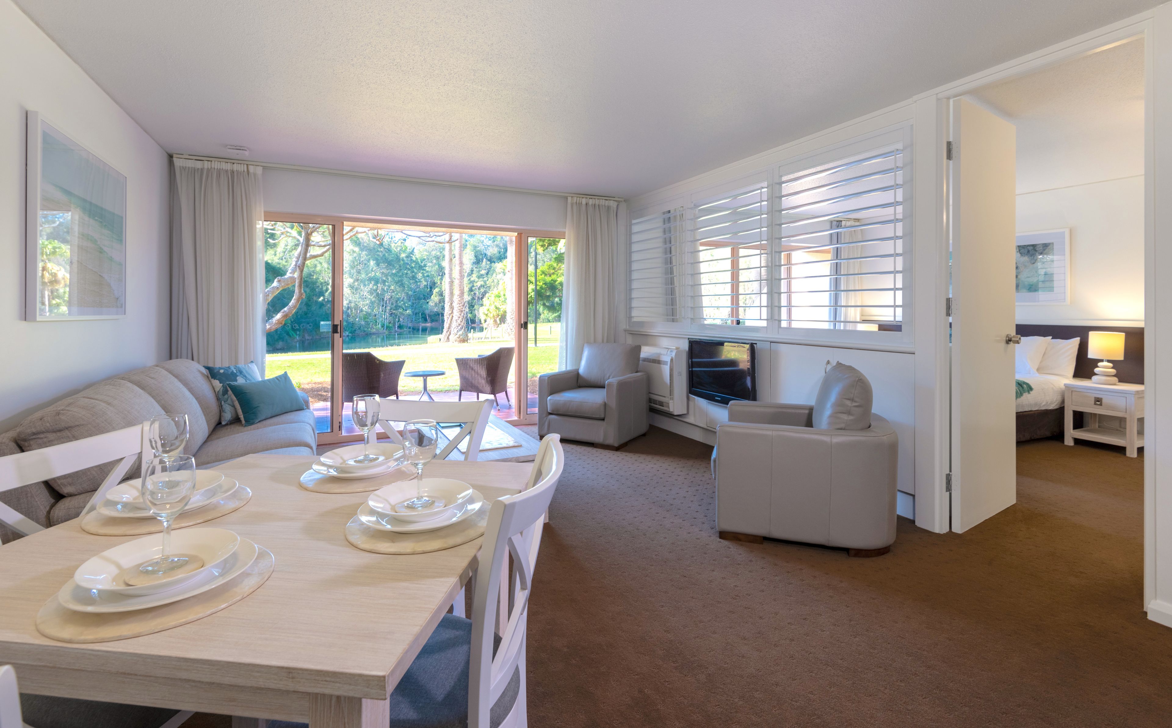 A spacious living room with a dining area, large windows, and a view of the outdoors.