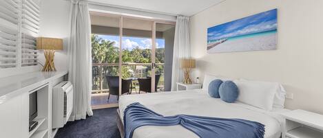 A hotel room with a bed, a desk, a chair, and a view of the outdoors.