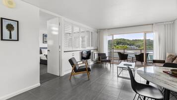 A modern hotel room with a balcony, a dining area, and a kitchen.