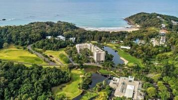 Vista aérea de un campo de golf con un edificio grande, una masa de agua y una playa.