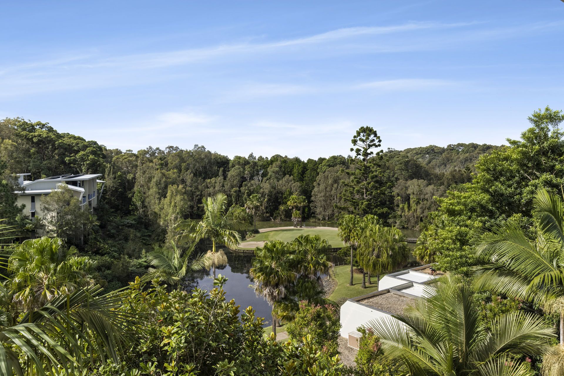 A modern house with a view of a golf course and dense forest.