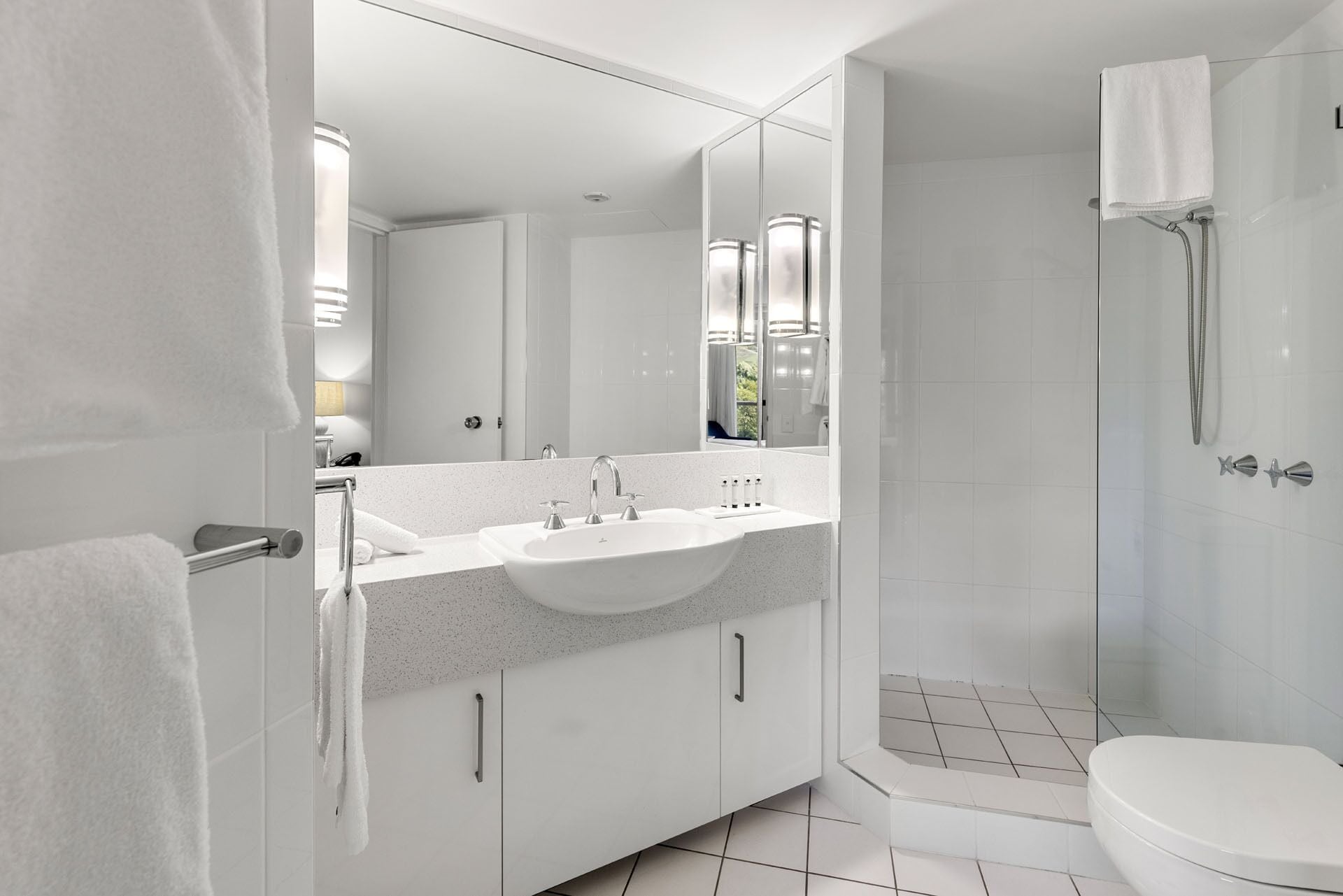 A modern bathroom with a large mirror, a sink, and a shower.
