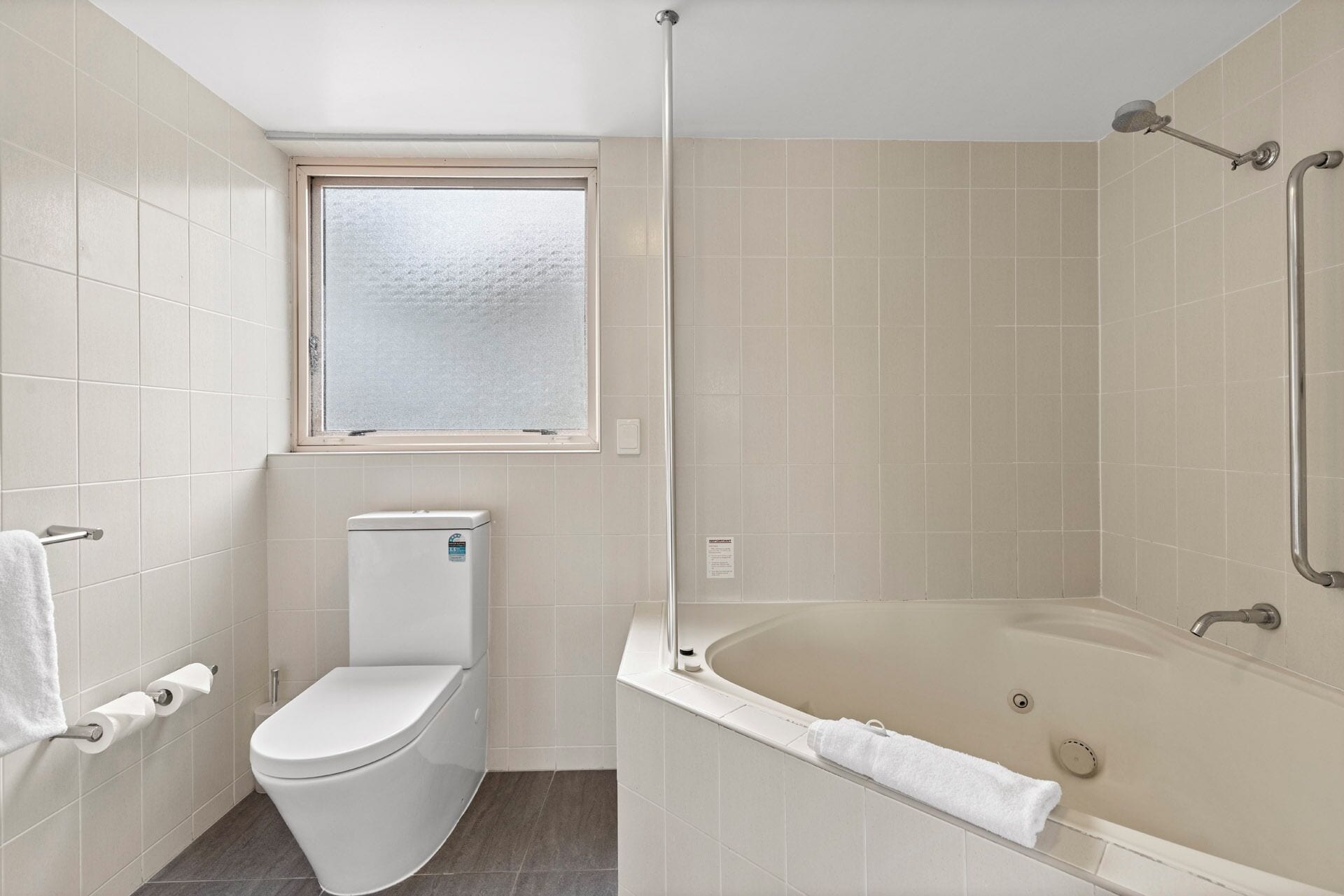 A modern bathroom with a toilet, a window, and a bathtub.
