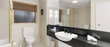Un baño moderno con inodoro, lavamanos y ducha.