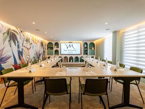 A conference room with a long table, chairs, a projector screen, and a mural with tropical leaves. - Hotel Mercure Rabat Sheherazade (Rabat)