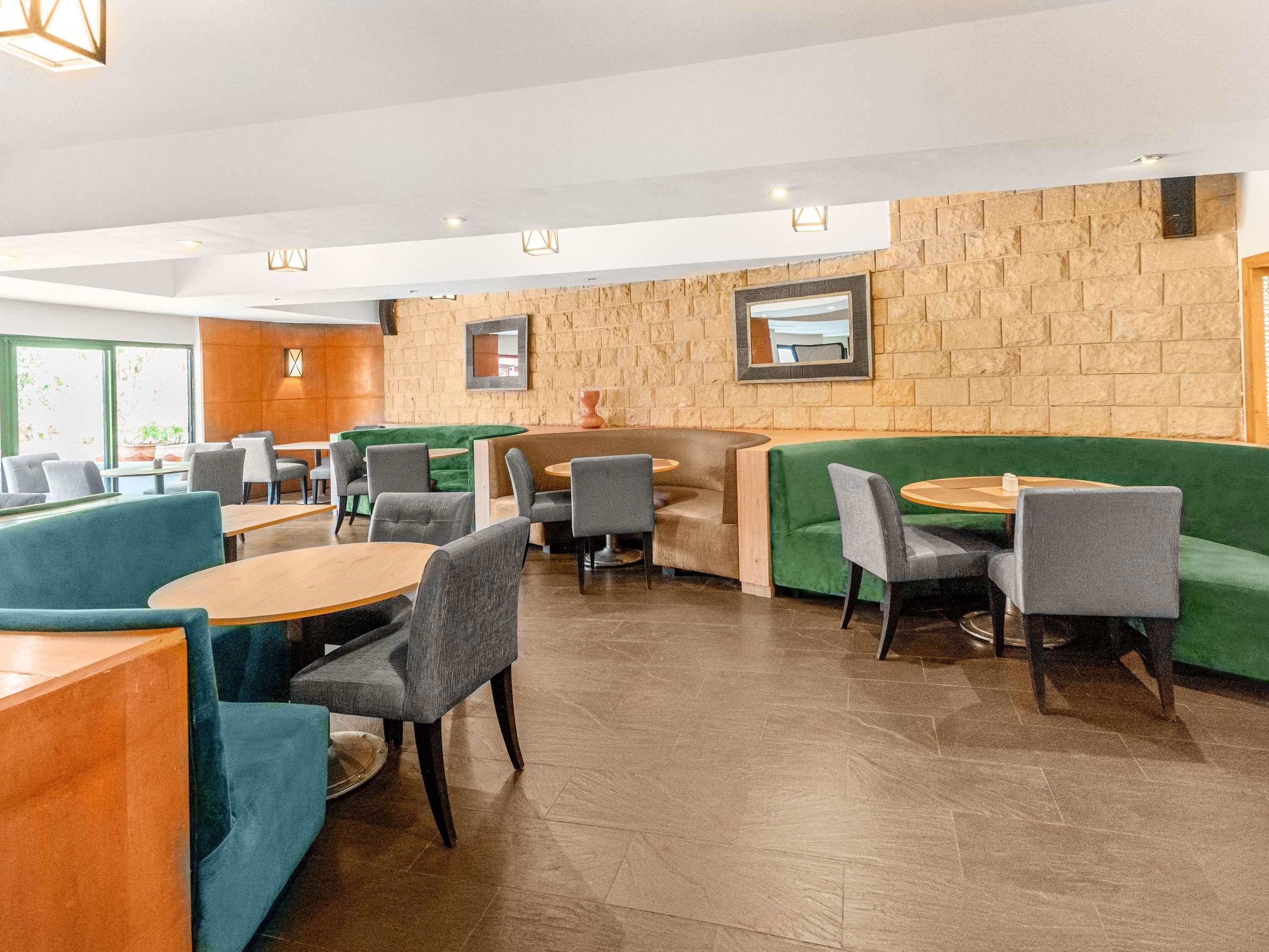 A modern interior with seating areas, tables, and a stone wall.