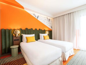 A hotel room with two beds, a checkered floor, and a large window with curtains.