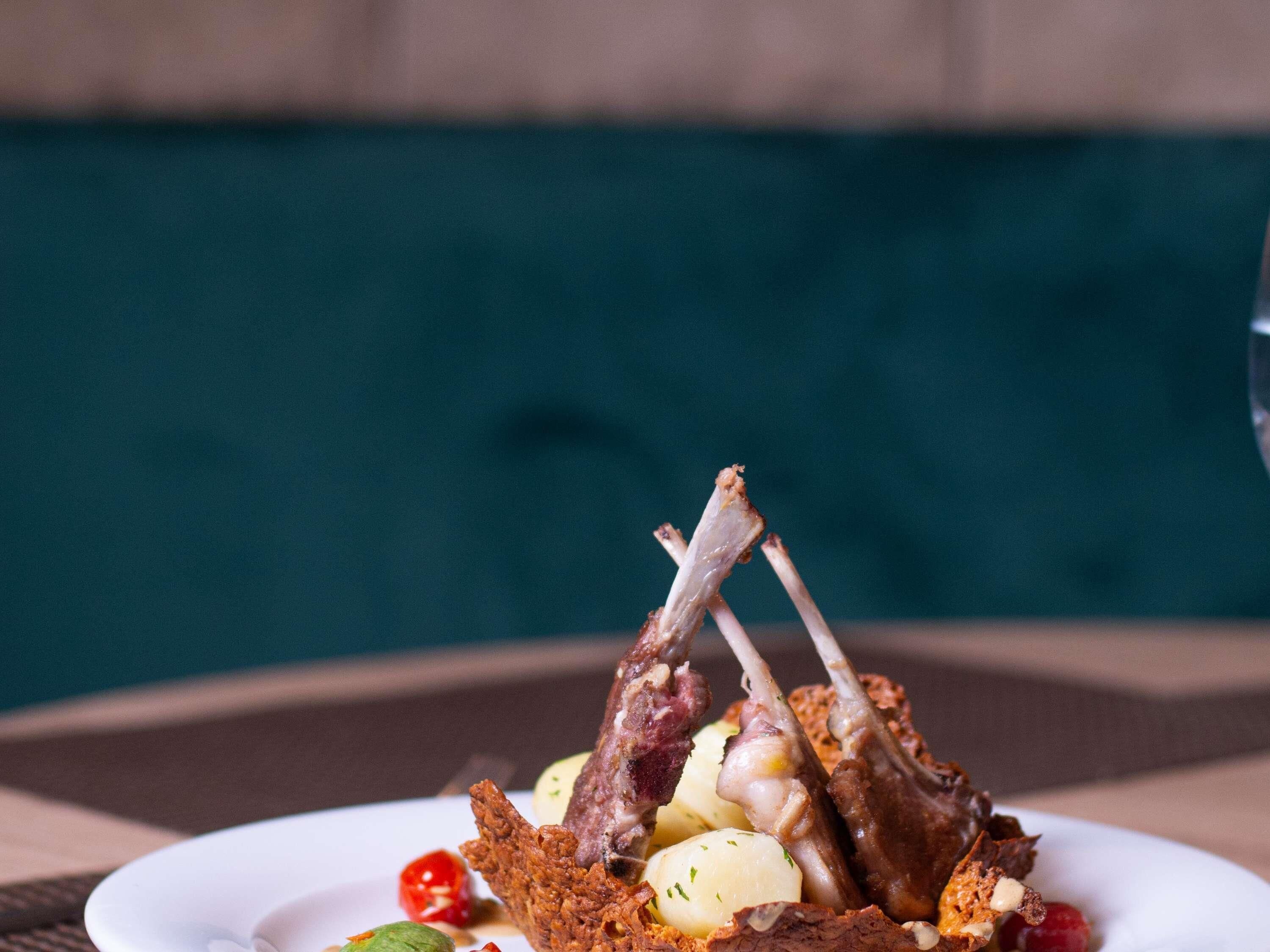Un plato con chuletas de cordero asadas, patatas y tomates cherry.