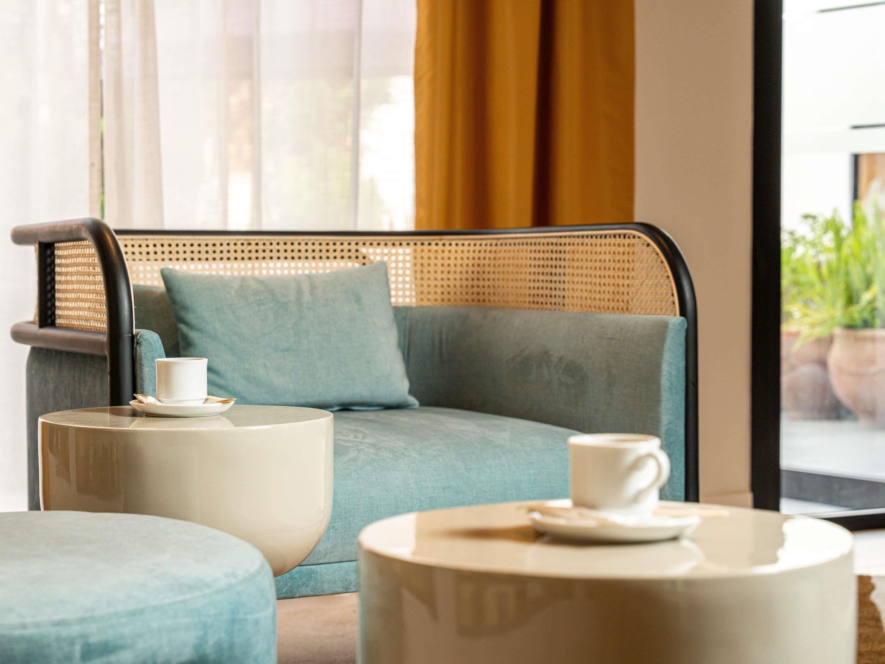 A modern room with a rattan sofa, a round coffee table, and a cushioned ottoman.