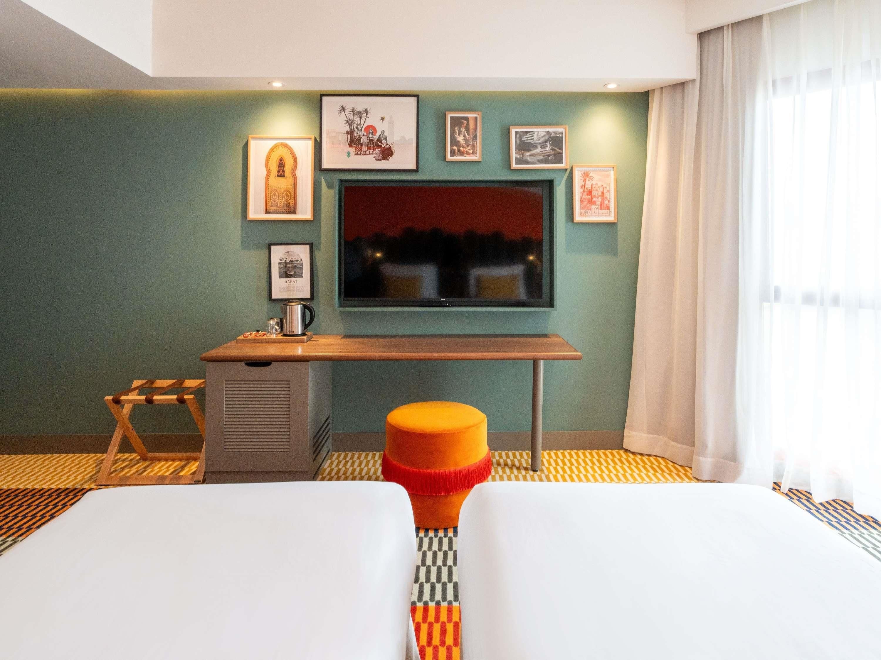 A hotel room with a bed, a desk, a television, and a window with curtains.