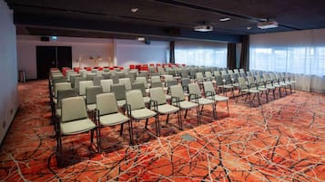 A conference room with rows of chairs, a carpeted floor, and a projector on the ceiling.