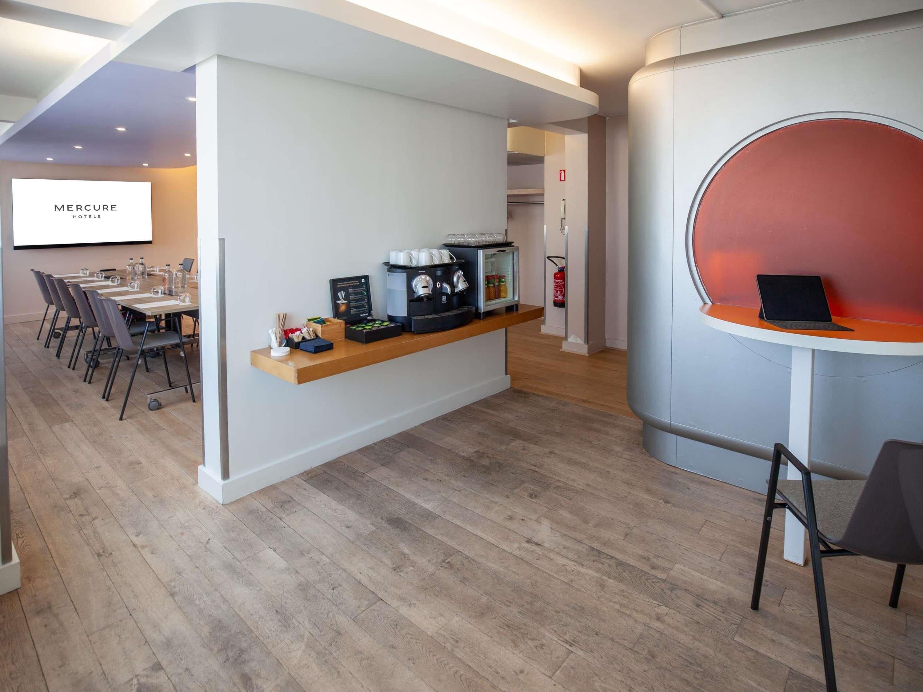 A conference room with a whiteboard, a coffee station, and a laptop on a stand.