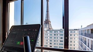 A treadmill in a room with a large window overlooking the Eiffel Tower. - Mercure Paris Centre Tour Eiffel (Paris)